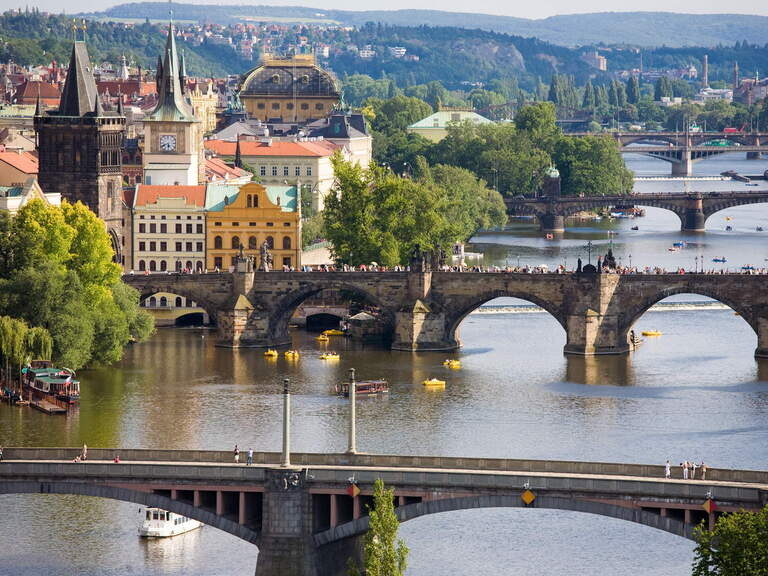 Eine Brücke spannt sich über einen Fluss und am Ufer stehen alte Gebäude